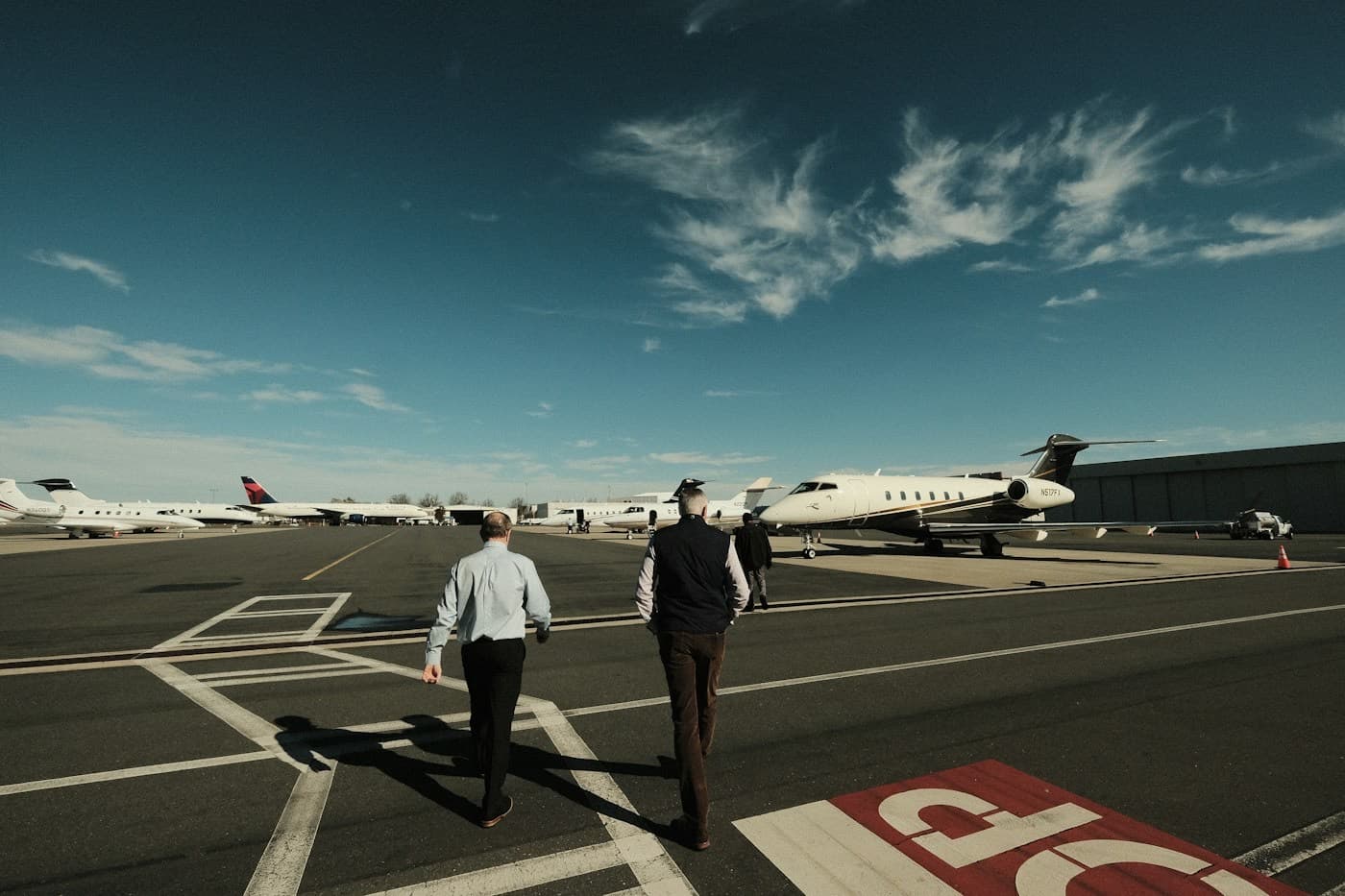 Dois executivos caminhando em direção a um jato no pátio do aeroporto