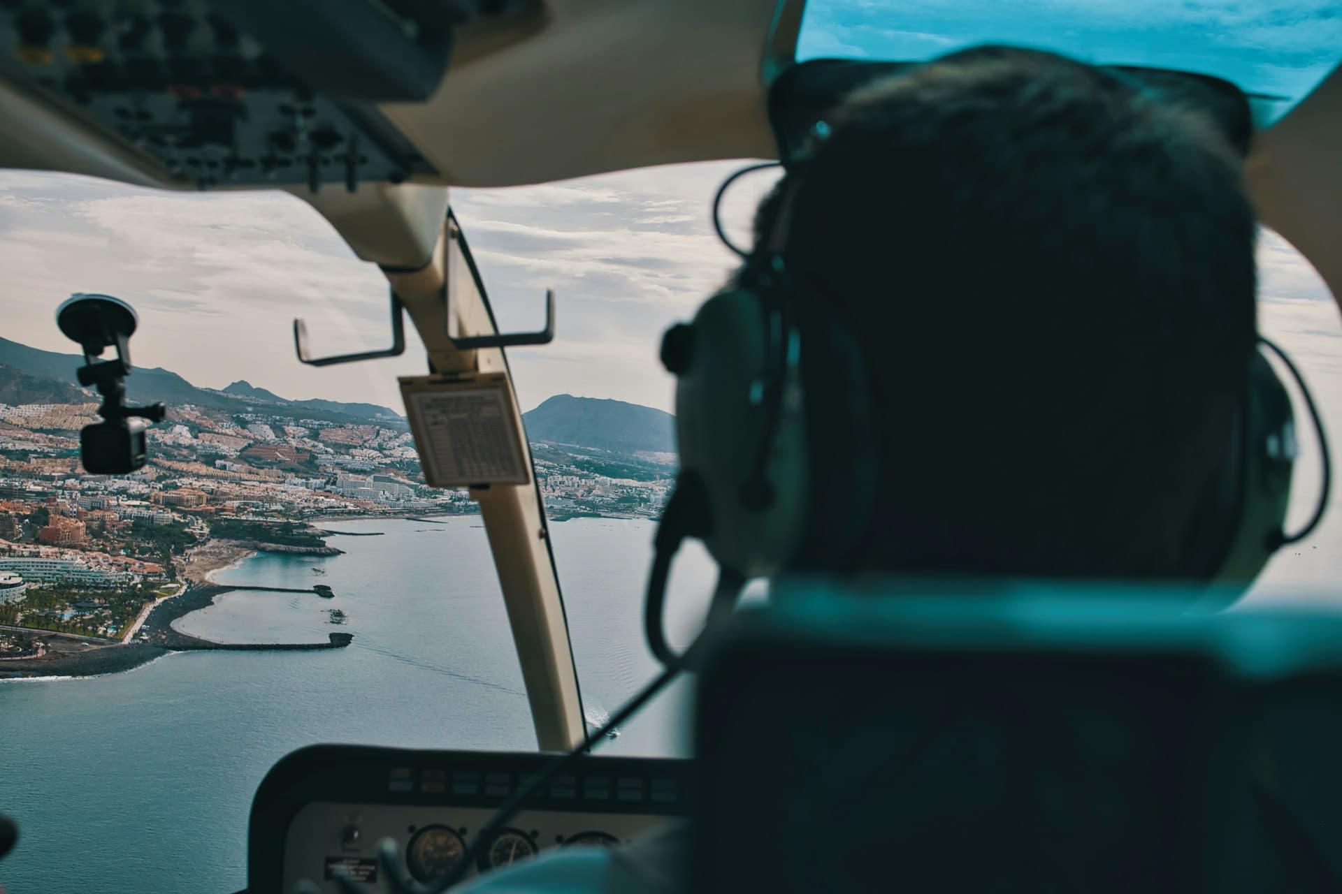 Piloto com fones de ouvido conduzindo um helicóptero sobre o litoral