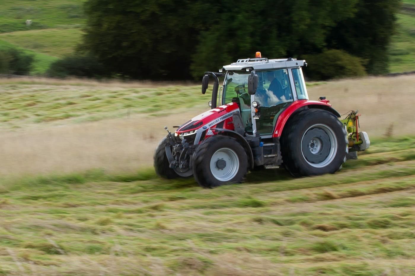 Trator vermelho trabalhando em um campo verde