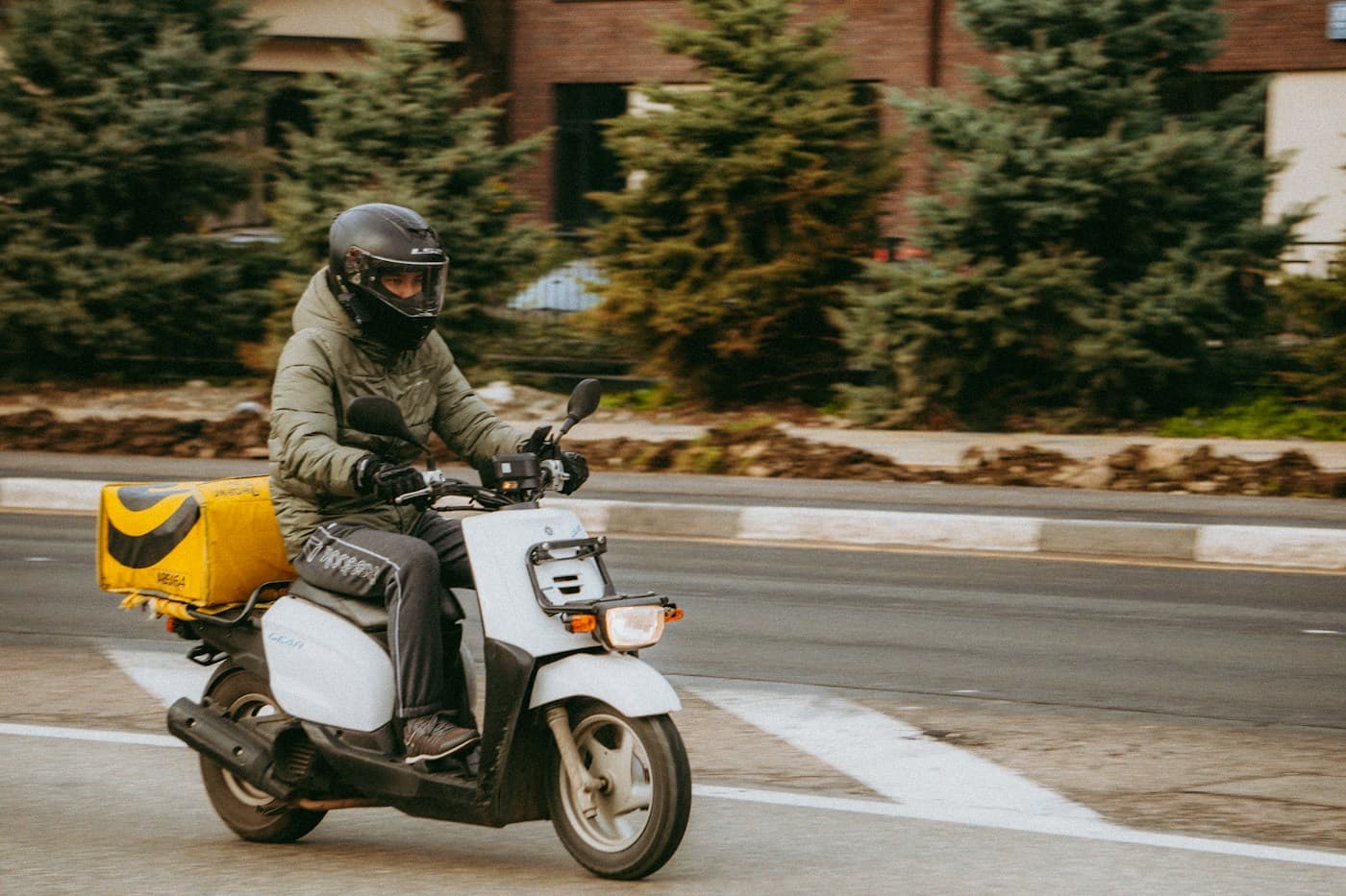 Entregador de moto com baú trabalhando na cidade