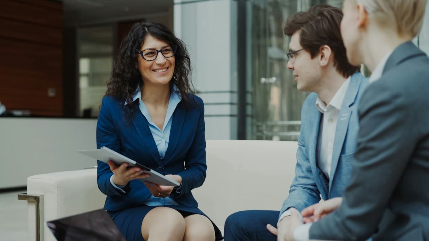Profissional sorrindo em uma conversa com dois colegas de trabalho