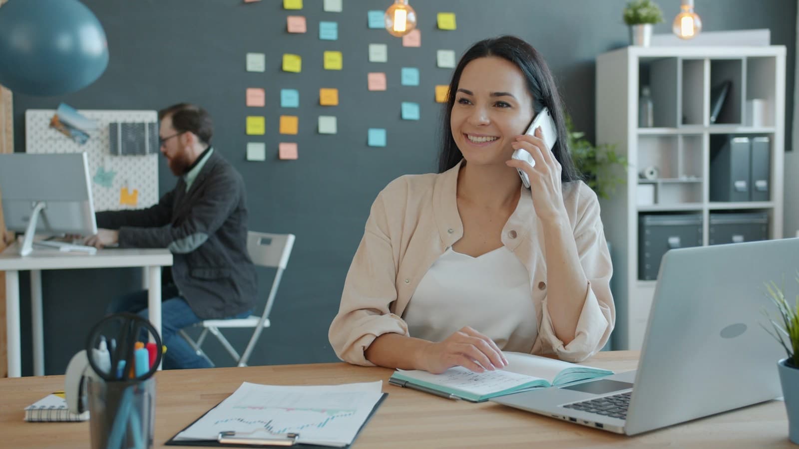 Atendente sorrindo enquanto fala ao telefone em um escritório
