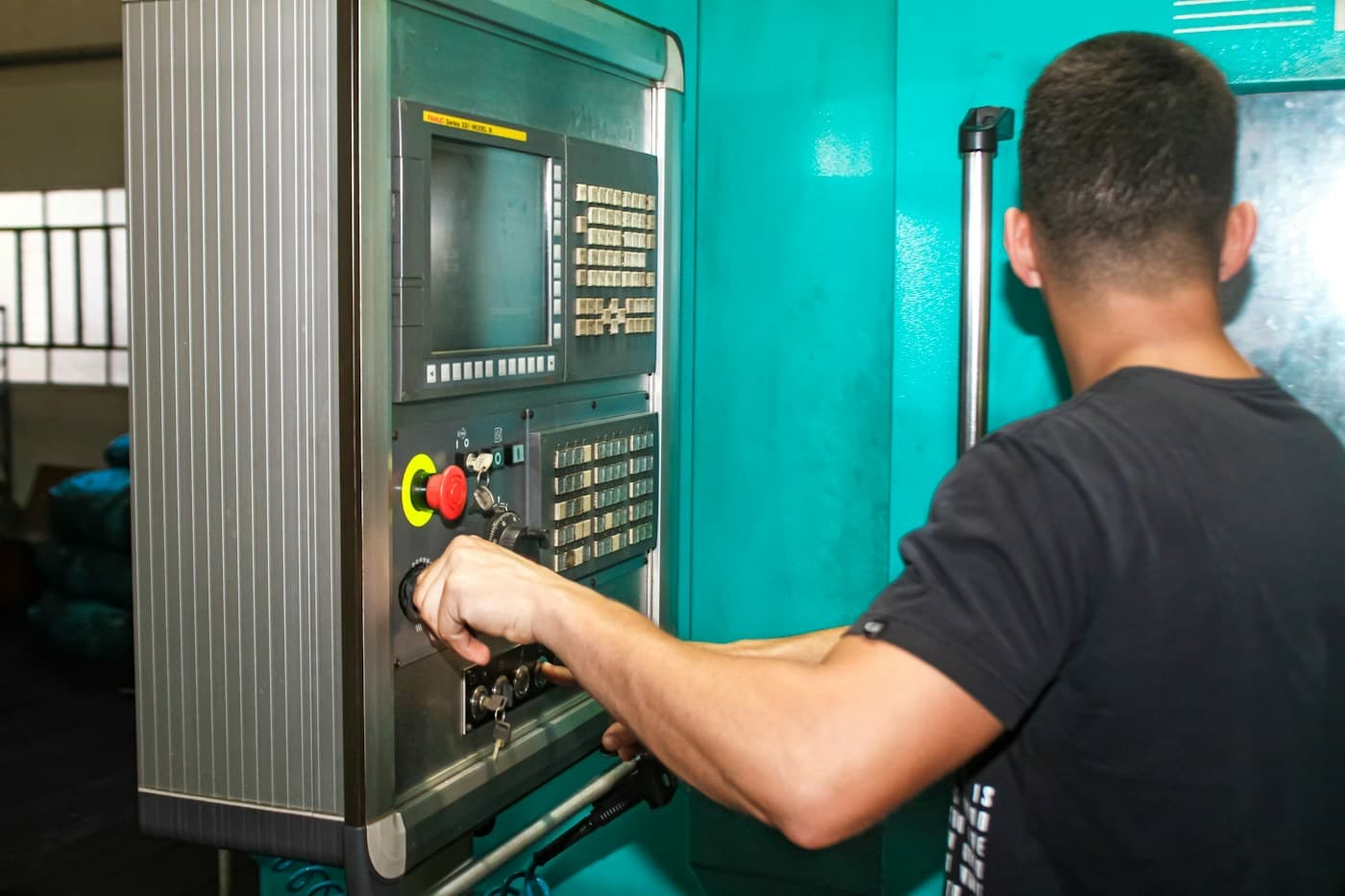 Operador ajustando o painel de uma máquina CNC