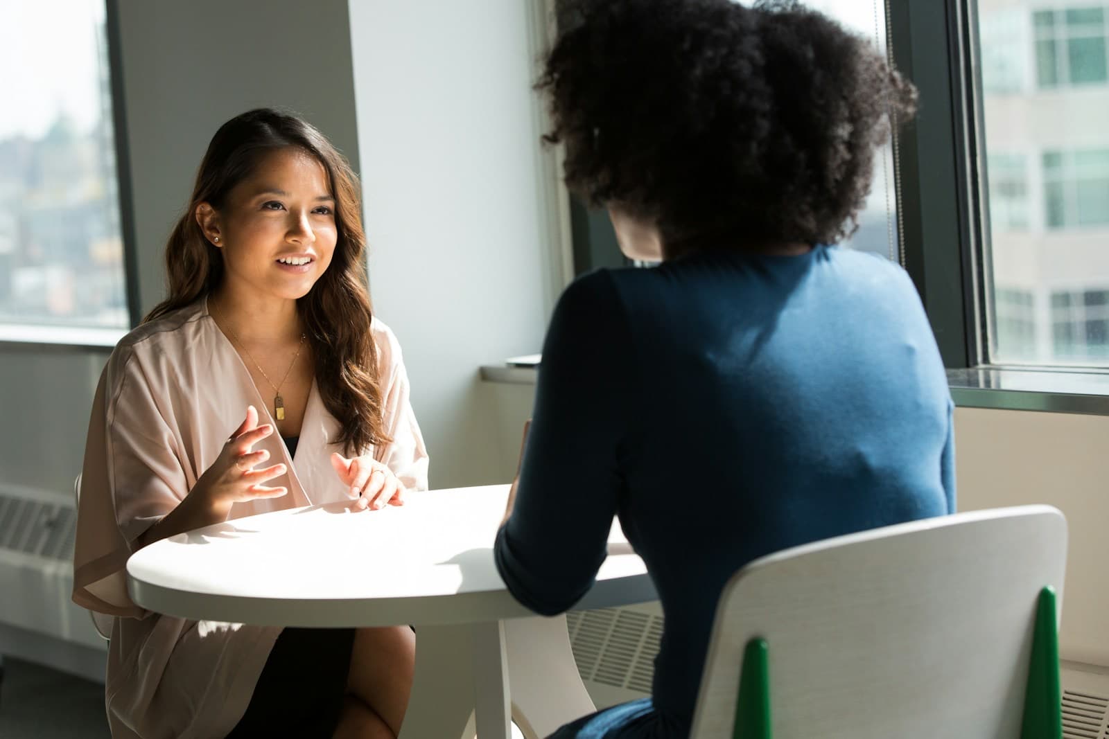 Consultora conversando com uma cliente à mesa