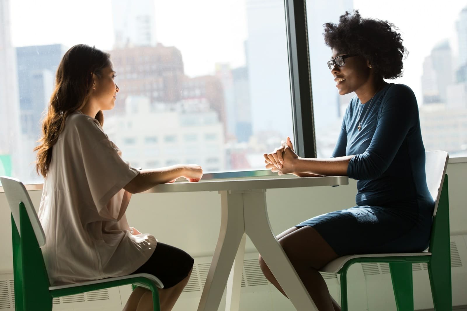 Duas colegas conversando à mesa em um ambiente de trabalho acolhedor
