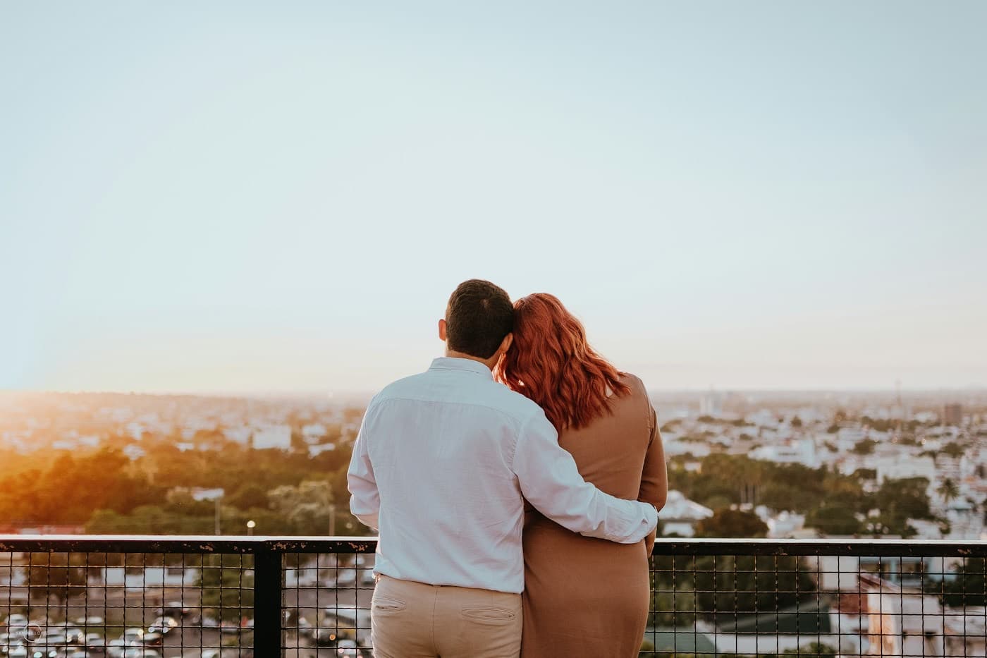 Casal abraçado apreciando a vista ao entardecer