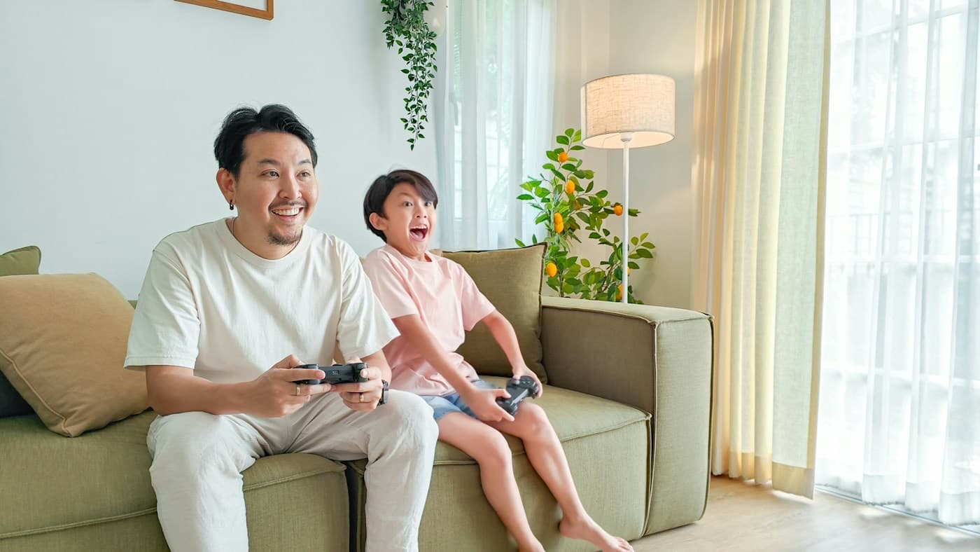 Pai e filho se divertindo com videogame no sofá de casa