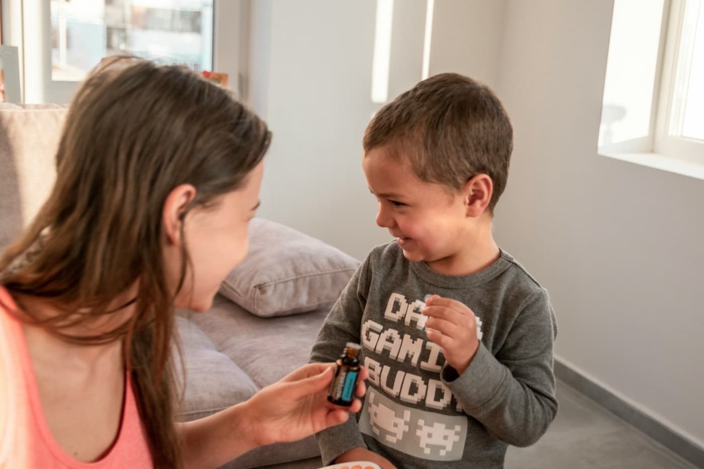 Mãe cuidando do filho pequeno, que sorri, na sala de casa