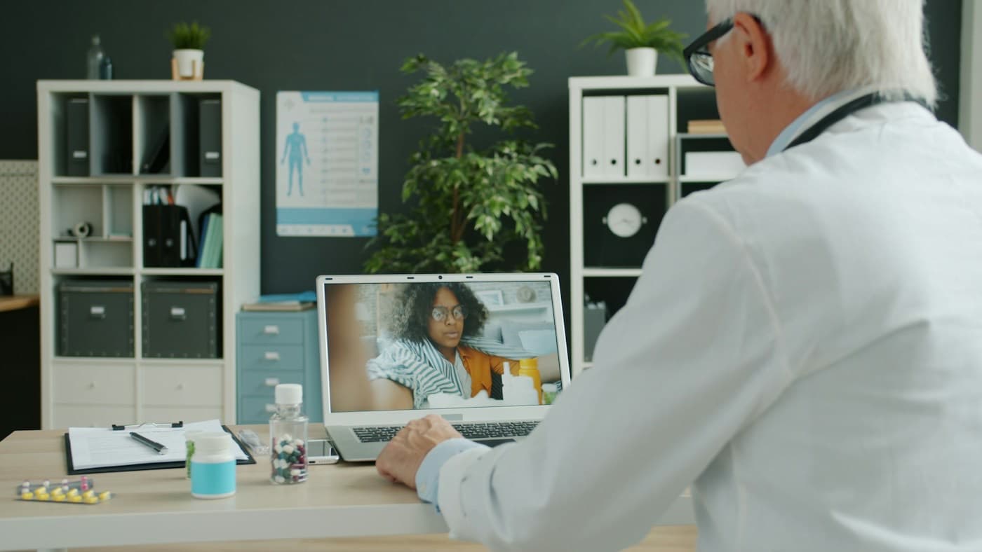 Médico atendendo uma paciente por videochamada no notebook