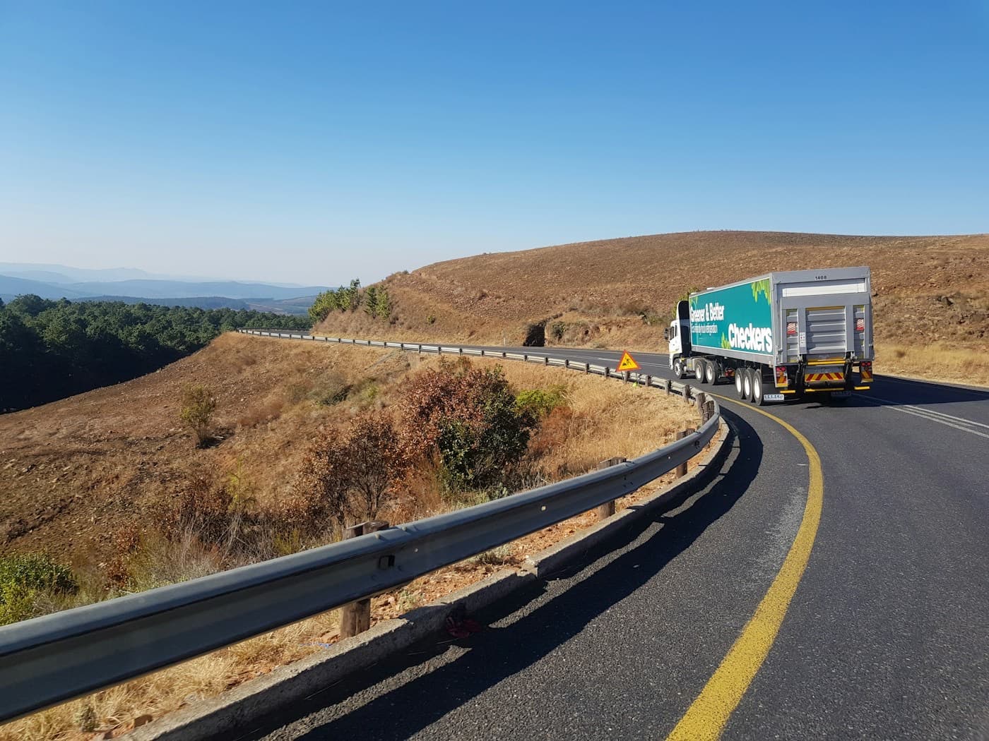 Caminhão trafegando por uma rodovia sinuosa em região de serra