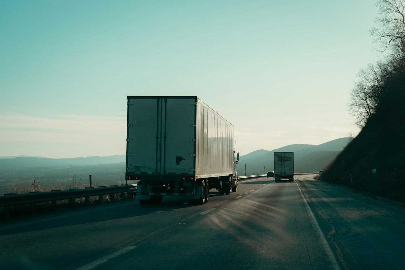 Caminhões trafegando em uma rodovia ao amanhecer