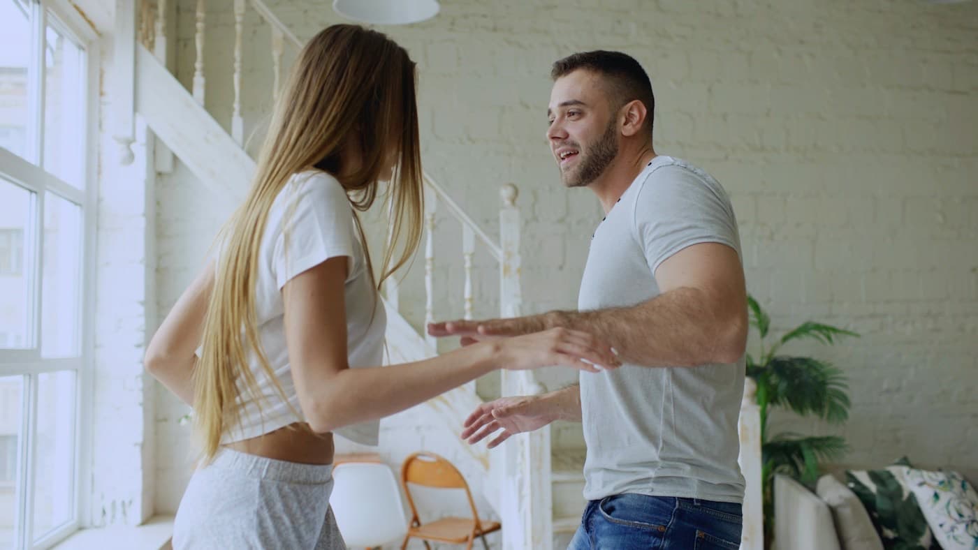 Casal jovem dançando e sorrindo na sala de casa