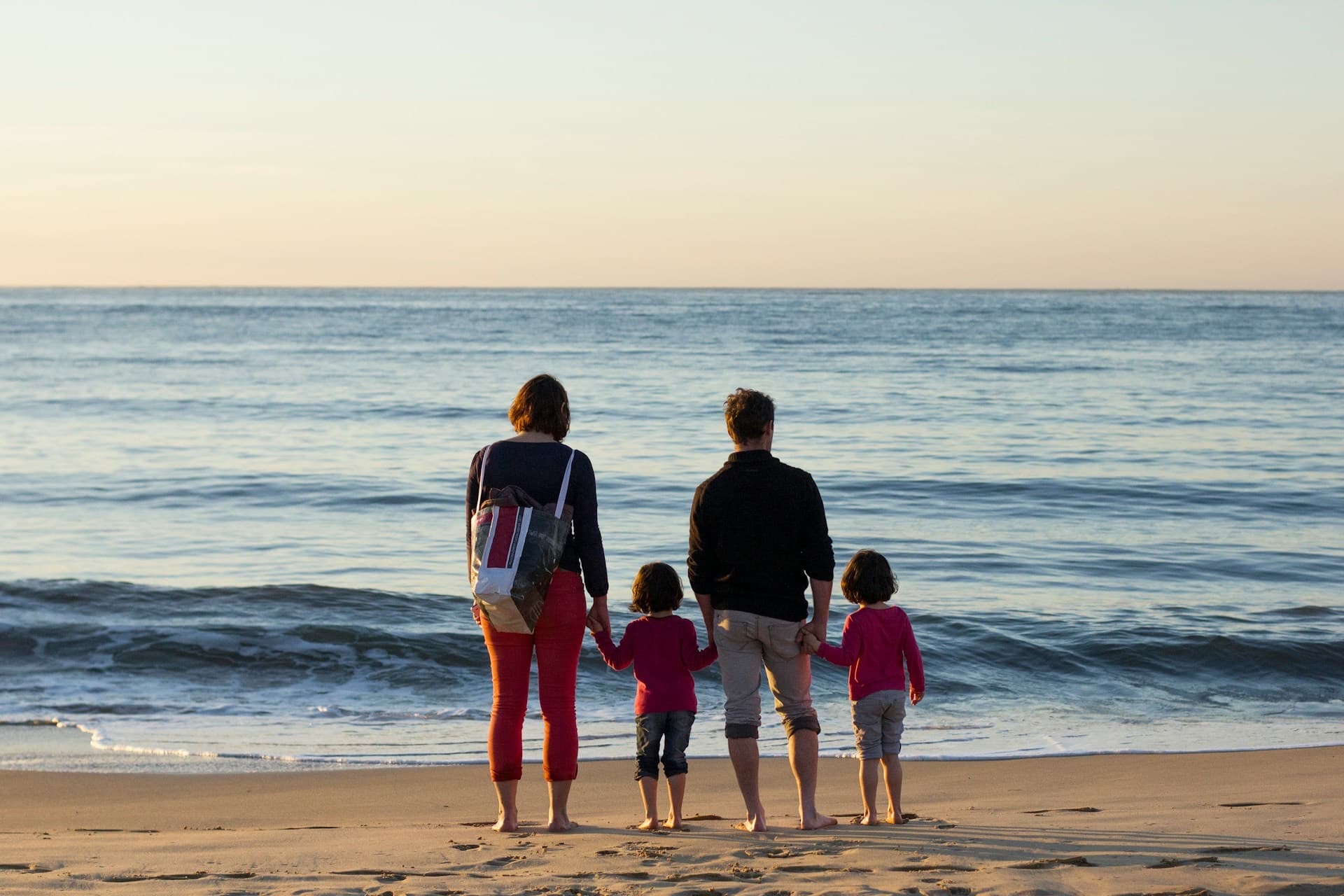 Família de mãos dadas à beira do mar